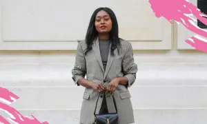 Frau in kariertem Blazer und dunklem Oberteil, perfekt für einen **business casual** Look. Sie trägt eine schwarze Handtasche.